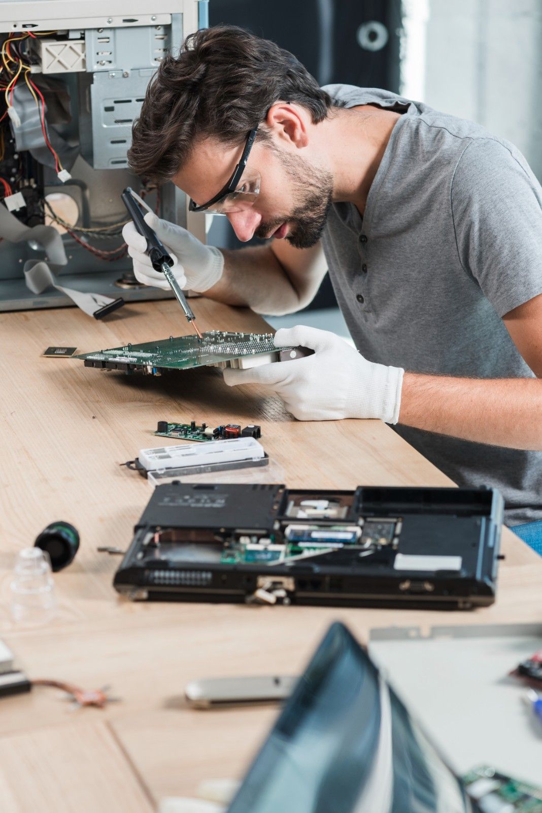 male-technician-repairing-computer-motherboard-wooden-desk (1)